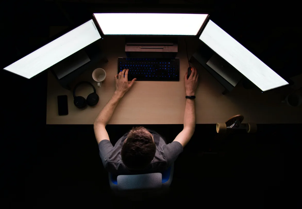 max-duzij-qAjJk-un3BI-unsplash (1) copie Un homme travaille devant trois écrans